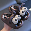 Pair of cartoonish brown sandals with white eyes and 'Cute' text held by a hand.