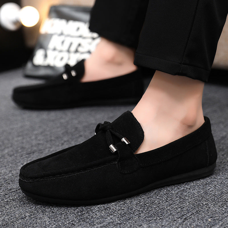 Black loafers worn by a person on a gray surface