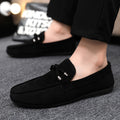 Black loafers worn by a person on a gray surface