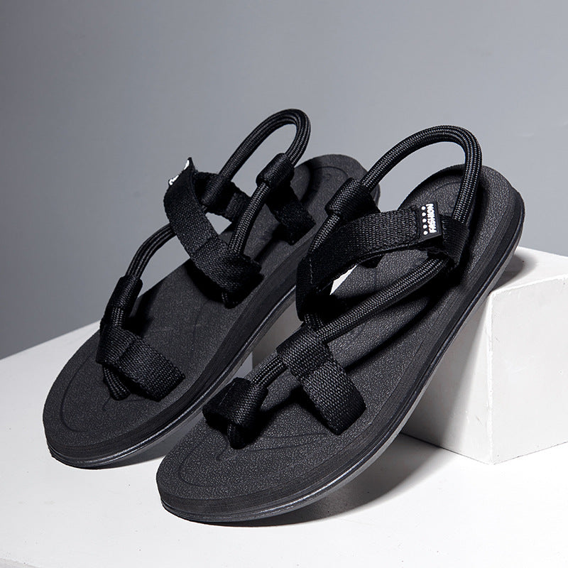 Black sandals with multiple straps on a white platform against a gray background