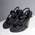 Black sandals with multiple straps on a white platform against a gray background