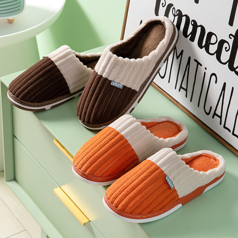 Pair of brown and orange slippers on a light green surface with a decorative sign in the background.
