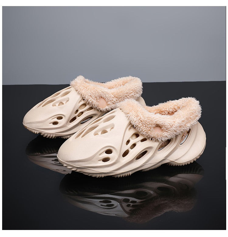 Beige slippers with fluffy trim on a reflective black surface with a gray background