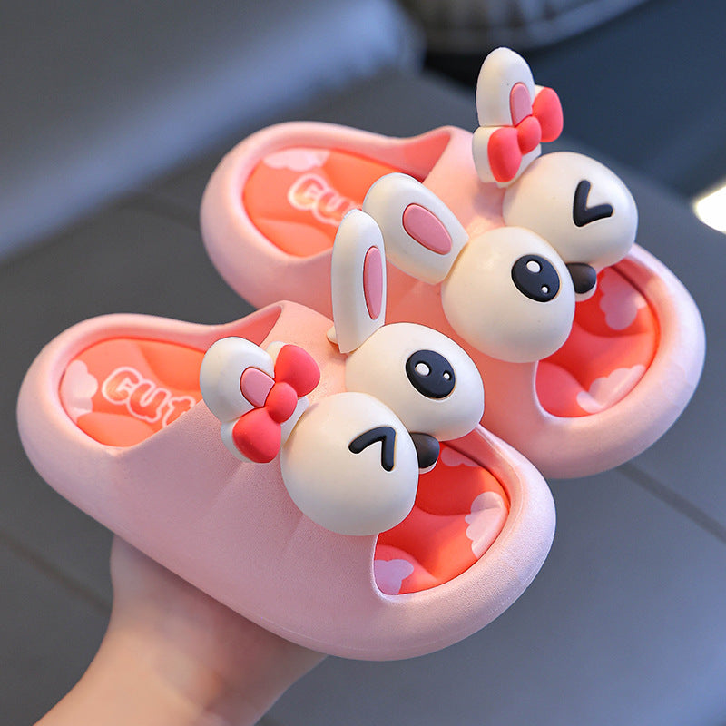 Pink cartoon-style slippers with bunny ears held by a hand on a blurred background