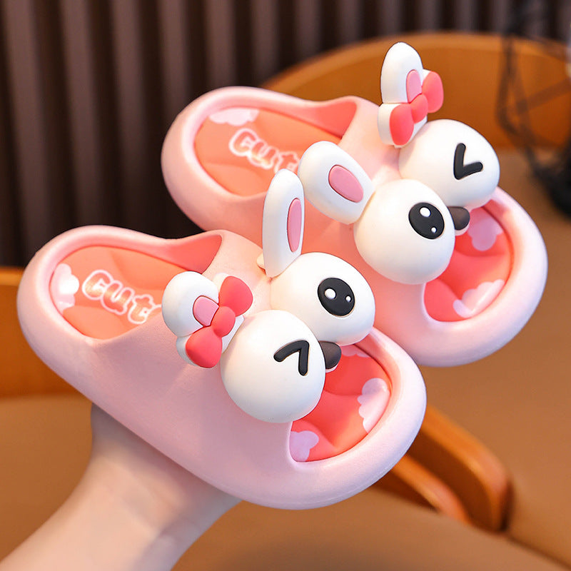 Pair of pink cartoon slippers with bunny ears held by a hand.