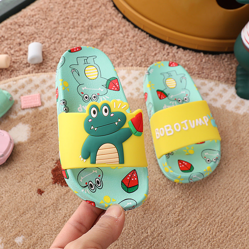 Colorful children's sandals with cartoon design held by a hand on a carpeted floor.