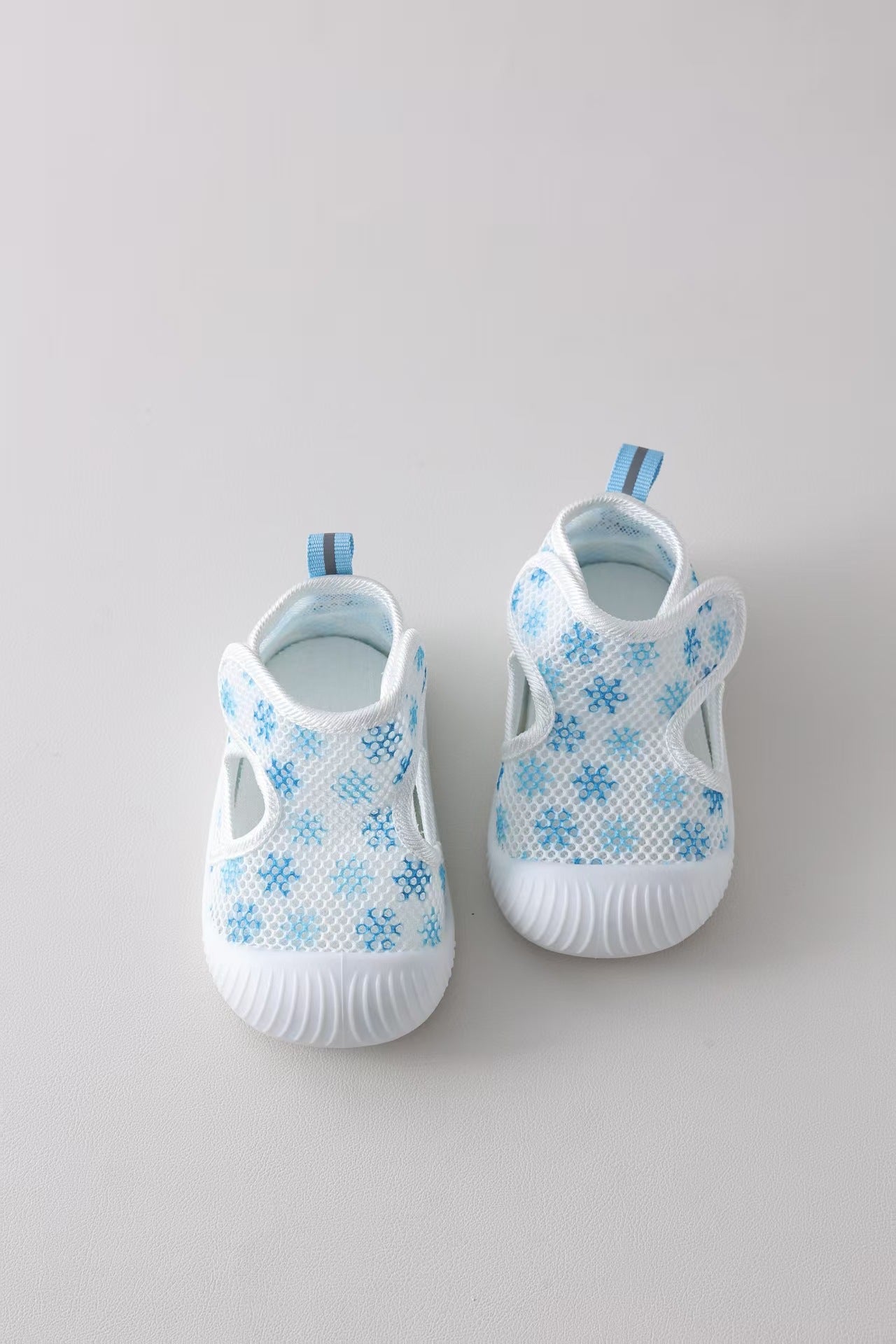 Pair of baby shoes with blue snowflake patterns on a gray background