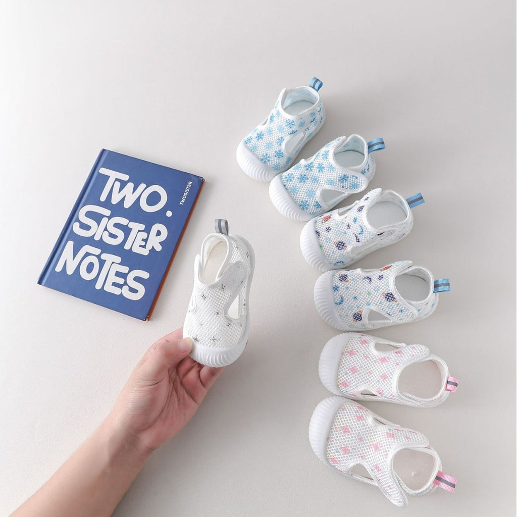 Baby shoes with a hand holding one, on a light gray background with 'Two Sister Notes' book.