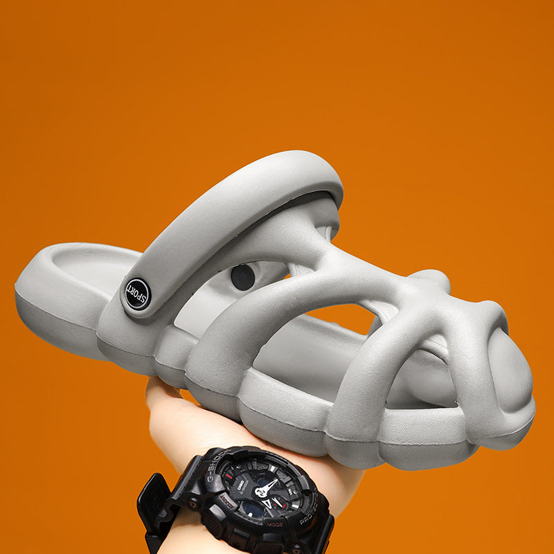 White sandal with a brand logo held by a hand wearing a black watch against an orange background