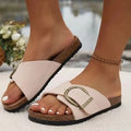 Beige sandals with a buckle detail worn by a person on a blurred background