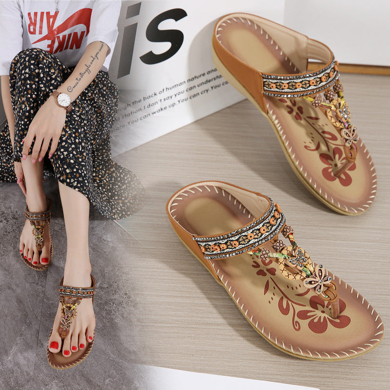 Decorative sandals with embellishments on a wooden surface, next to a person wearing similar sandals.