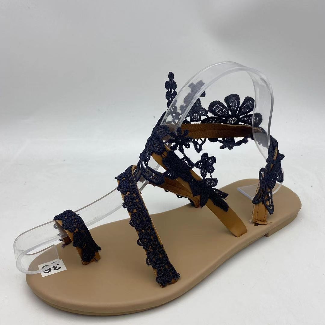 Beige sandal with navy lace details on a white background