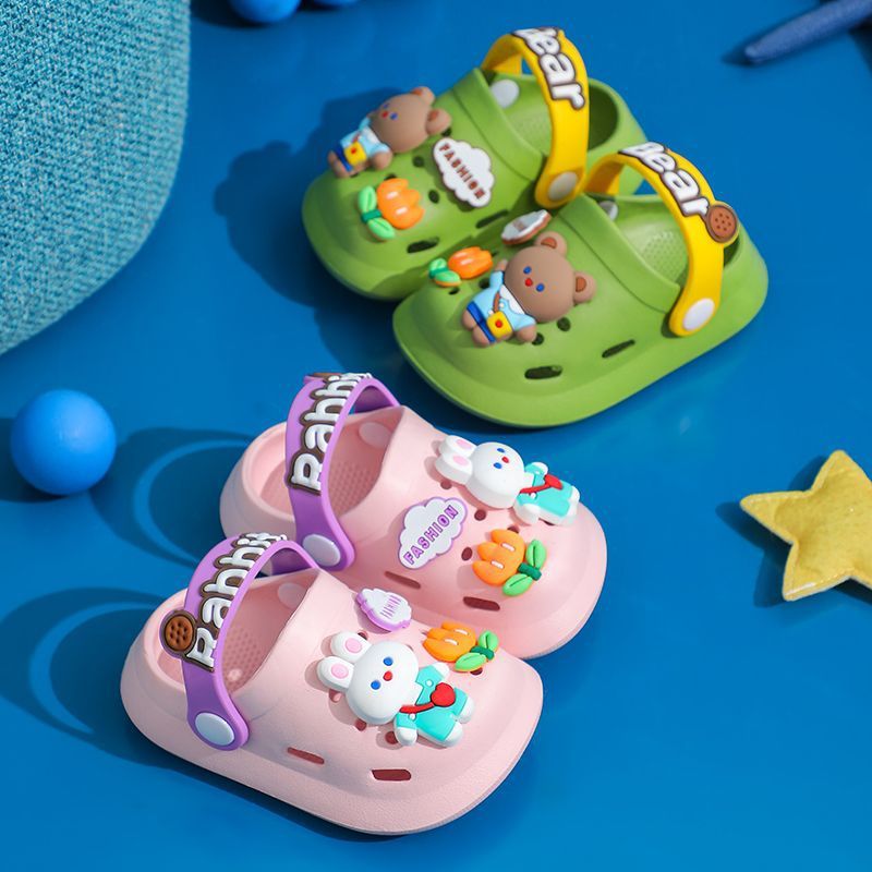 Pair of green and pink children's sandals with cartoon character designs on a blue background.