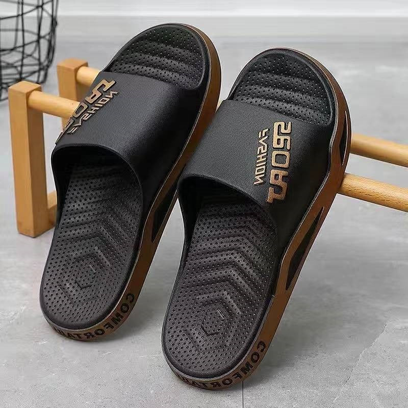 Black slides with brown soles on a wooden stand against a gray background