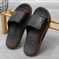 Black slides with brown soles on a wooden stand against a gray background