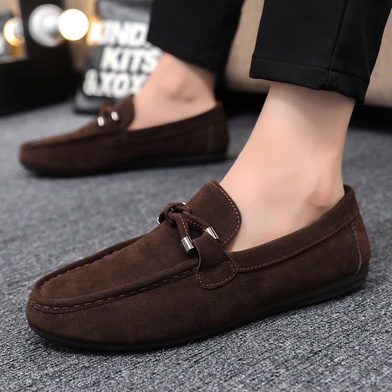 Brown loafers worn by a person on a gray floor.