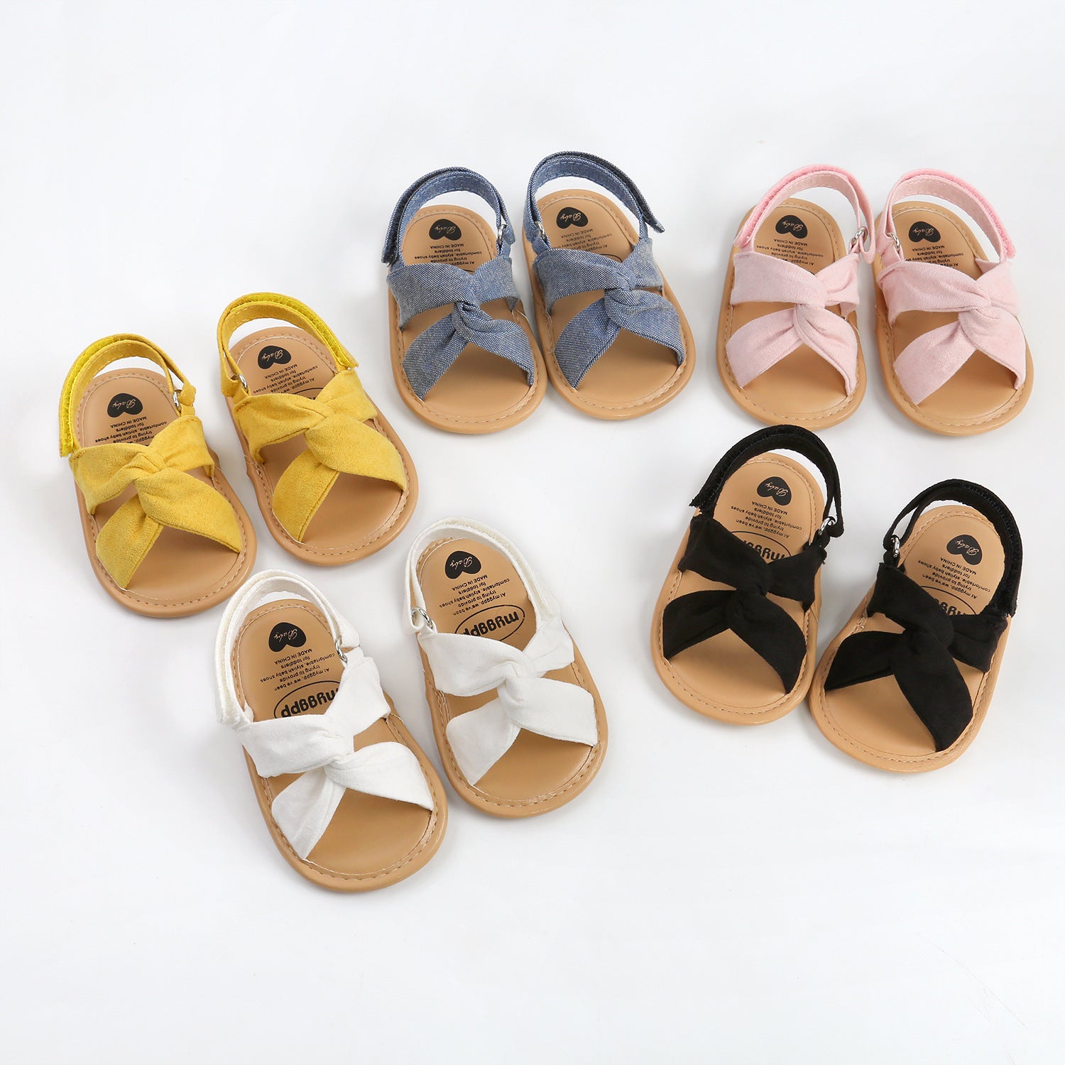 Set of colorful baby sandals with bow details on a white background