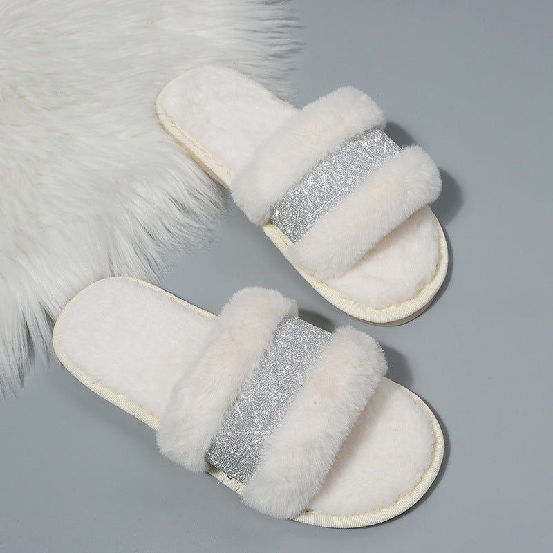 White slippers with fluffy texture and silver glittery straps on a gray background
