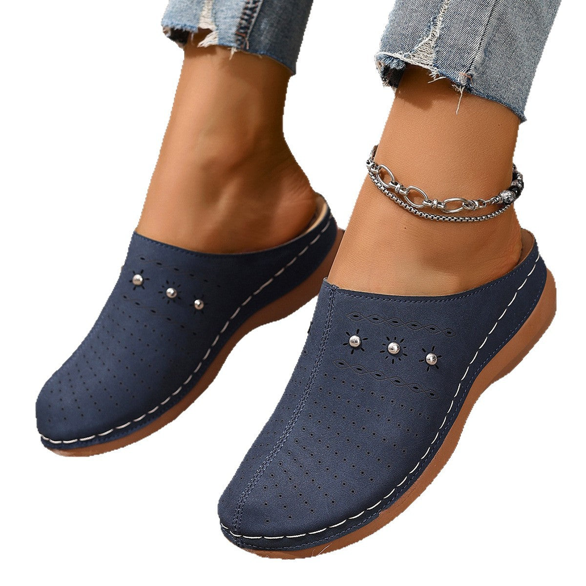 Navy blue clogs with pearl embellishments worn with denim jeans on a white background