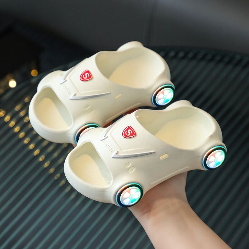 Pair of futuristic-looking shoes with glowing elements held by a hand on a dark textured surface.