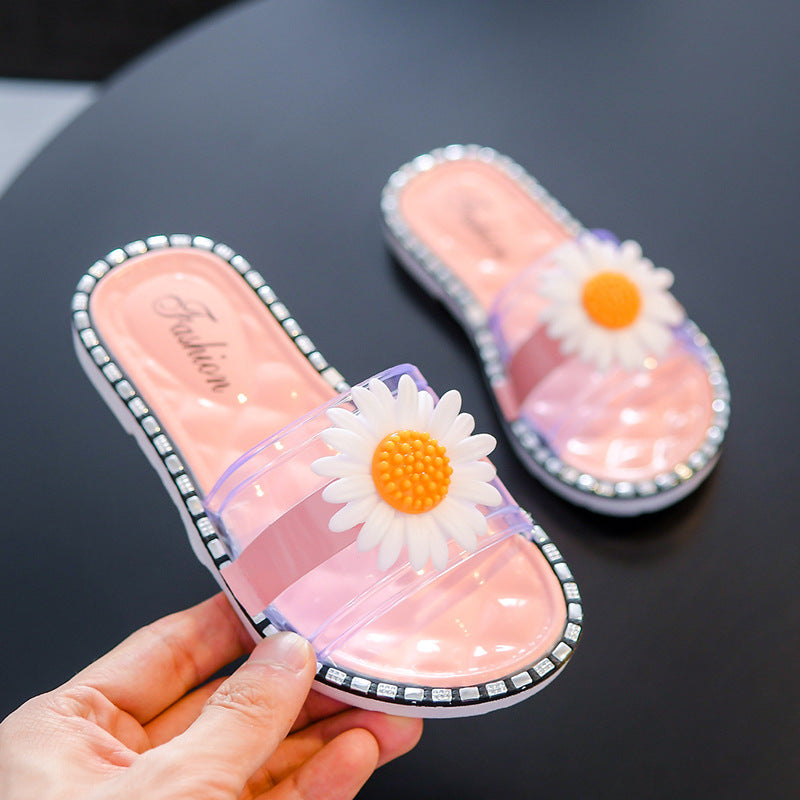 Pink slippers with daisy flowers held by a hand on a black background