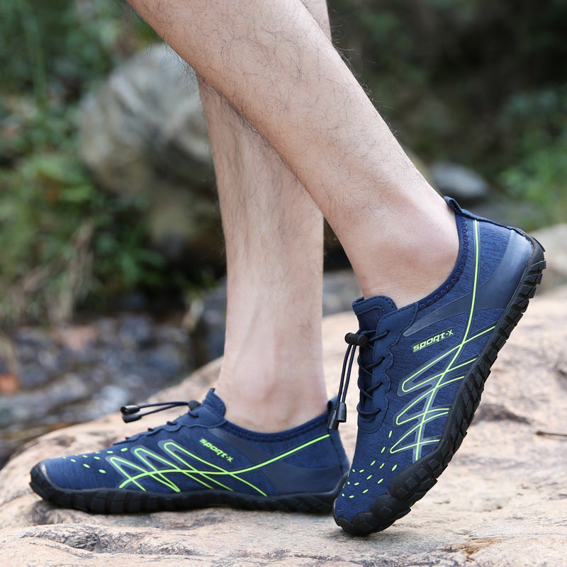 Blue water shoes with green accents worn by a person on a rocky surface.