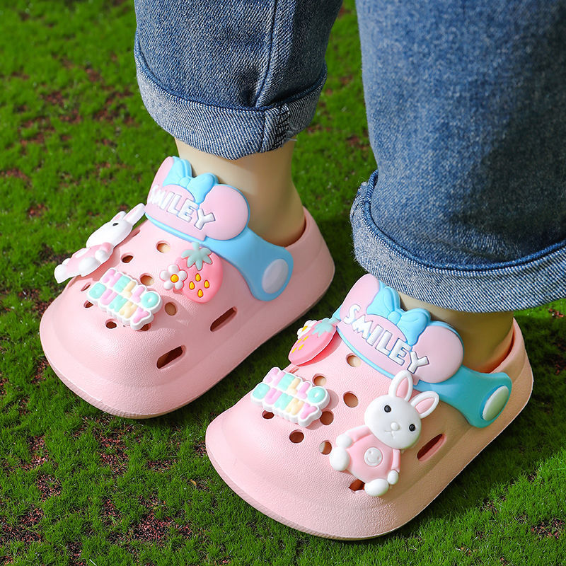 Children's pink sandals with cartoon designs on a grassy background