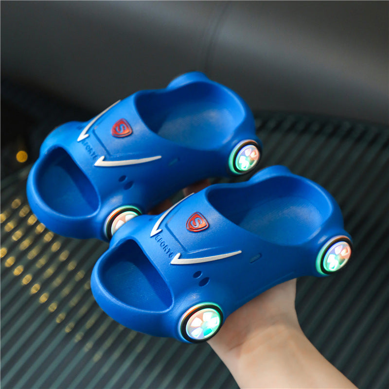 Blue children's shoes with glowing wheels held by a hand on a dark textured surface