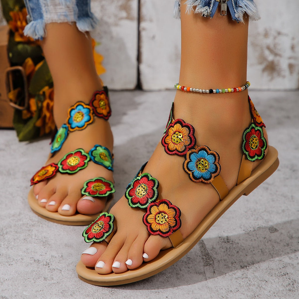 Colorful floral sandals worn with a denim skirt on a light background