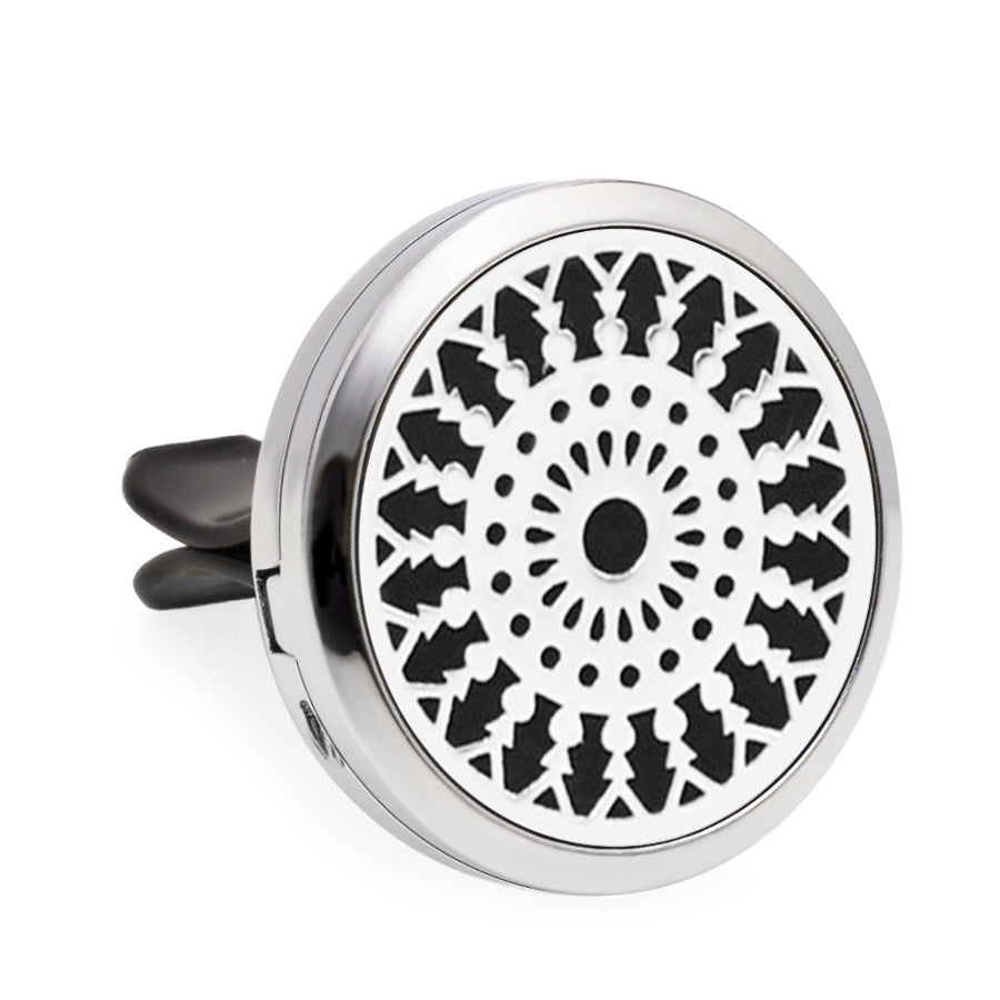 Round metallic car air freshener with black geometric pattern on a white background