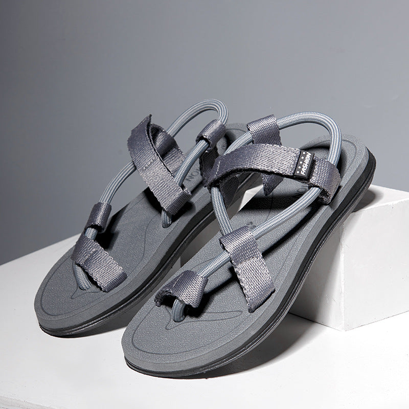 Pair of gray sandals on a white platform with a gray background