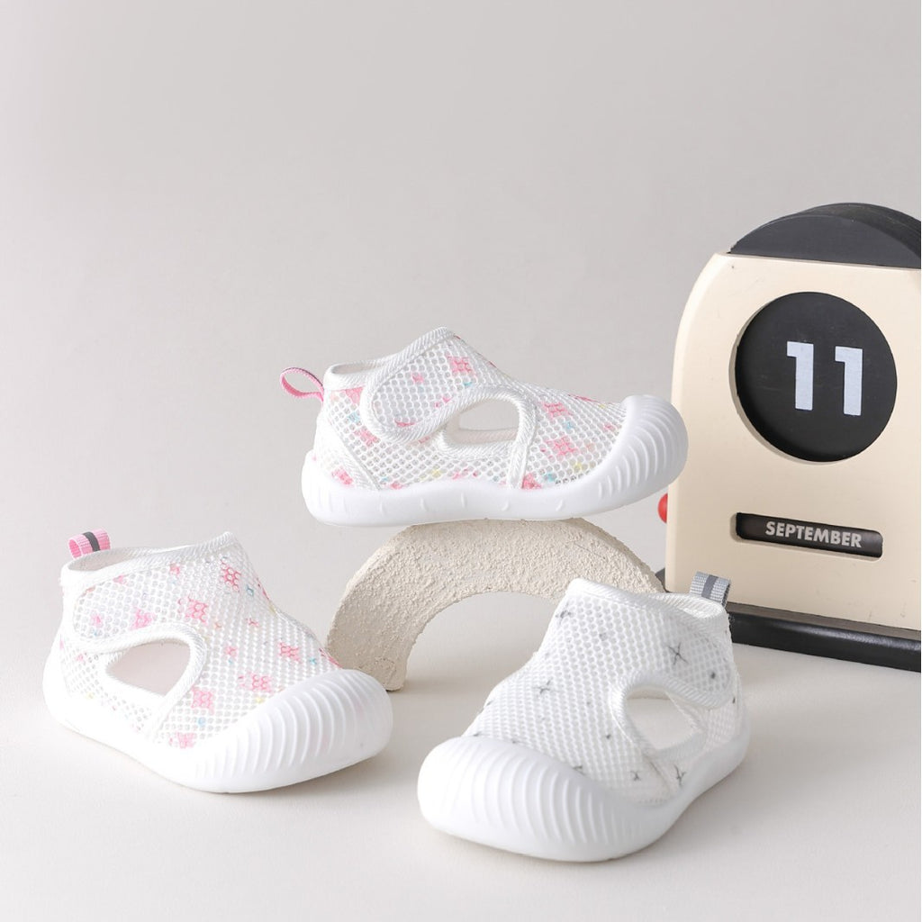 White baby shoes with pink floral patterns on a light gray background with a calendar.