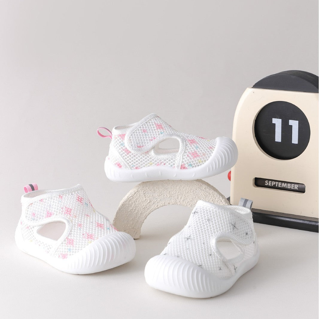 White baby shoes with pink floral patterns on a light gray background with a calendar.