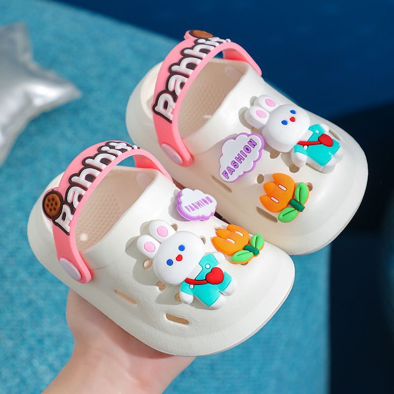 Children's sandals with cartoon character design held by a hand against a blue background