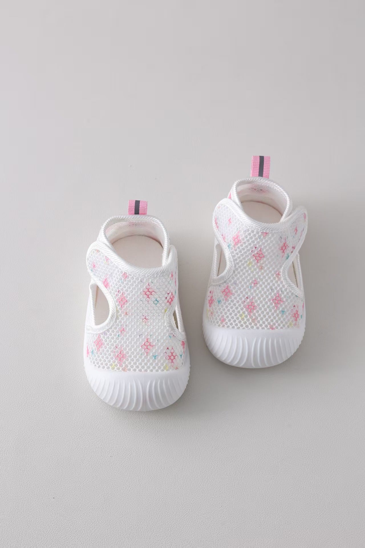 White baby shoes with floral patterns on a light gray background
