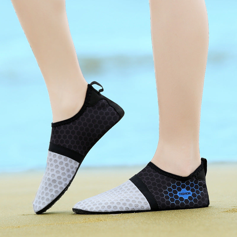 Black and gray beach shoes worn on feet with a blurred background
