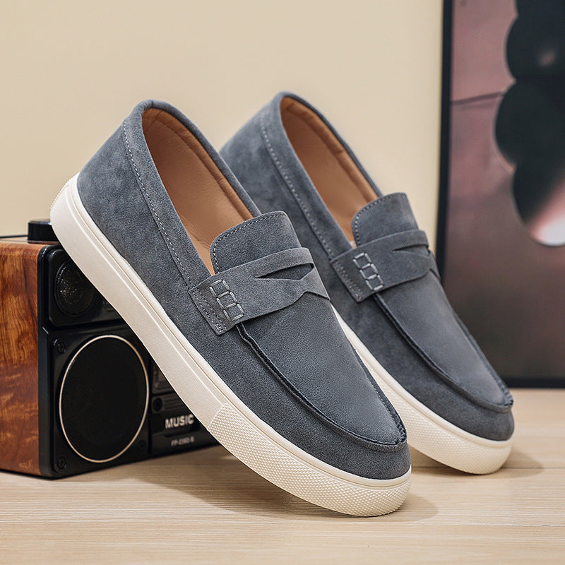 Pair of blue loafers with white soles on a wooden surface.