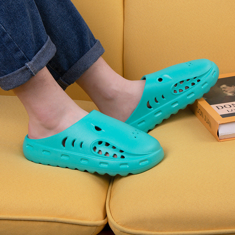 Teal clogs worn on feet sitting on a yellow couch.