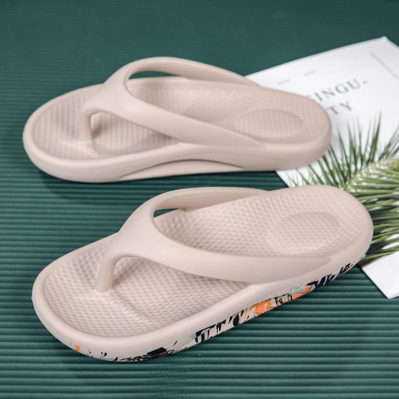 Pair of white flip-flops with a floral pattern on a green surface.