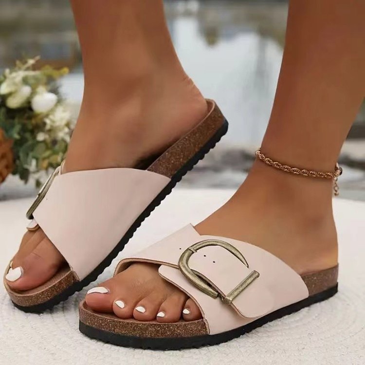 Beige sandals with a buckle detail worn by a person on a blurred background